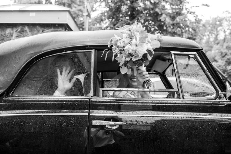 Nuotaka su vestuvine puokšte vintažiniame automobilyje mojuoja – juodai balta vestuvių nuotrauka, Birute Bras Photography