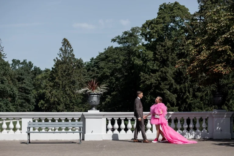Pora eina terasoje su medžiais fone, nuotaka rožinėje suknelėje – vestuvių nuotrauka, Birute Bras Photography