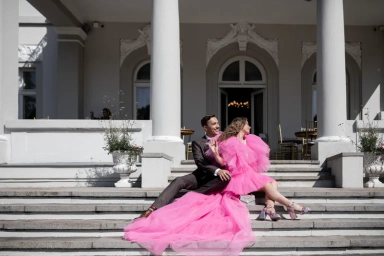 Pora sėdi ant rūmų laiptų, nuotaka rožinėje suknelėje – elegantiškas vestuvių portretas, Birute Bras Photography