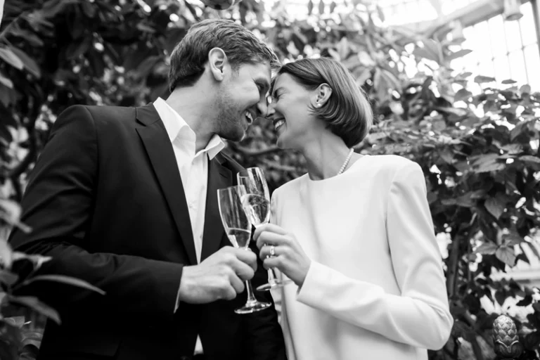 Pora su šampano taurėmis šiltnamyje – juodai balta elegantiškas vestuvių portretas, Birute Bras Photography